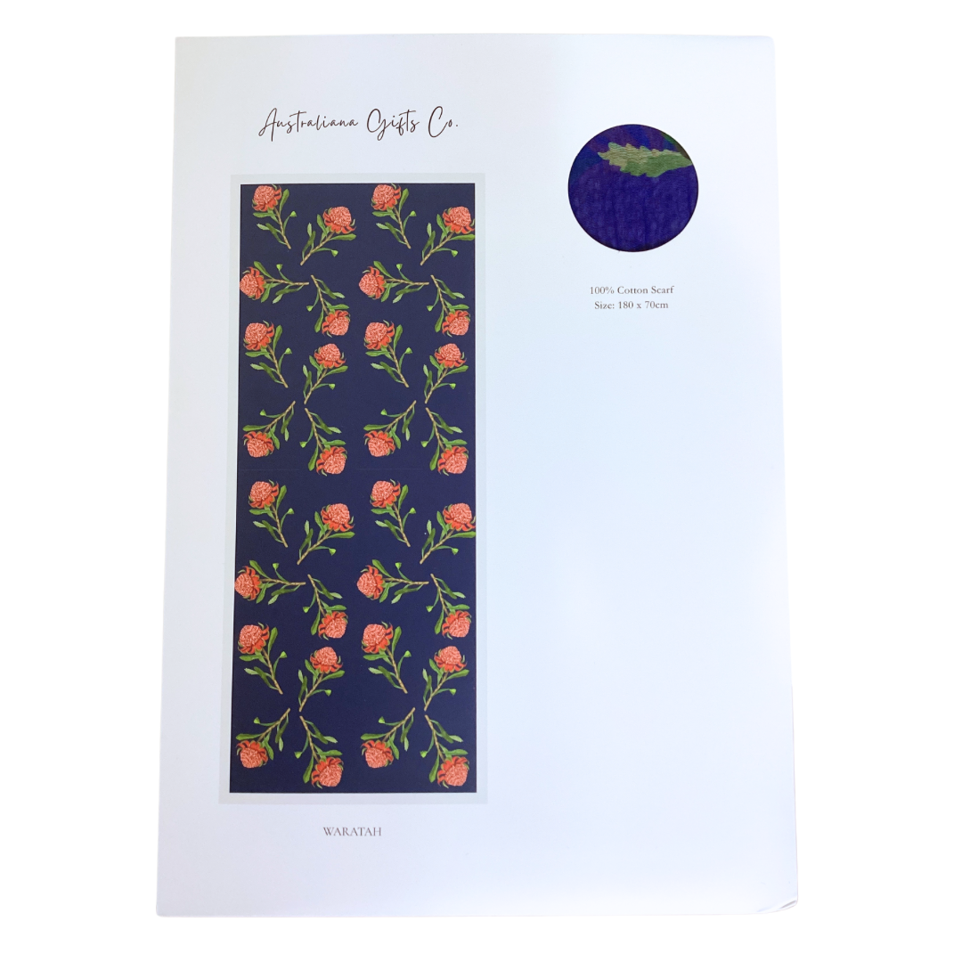 a lightweight ladies cotton scarf that has a navy blue background and bright pink Waratah flowers with green stems and leaves. The scarf is packaged in a white envelope with information about the flower.