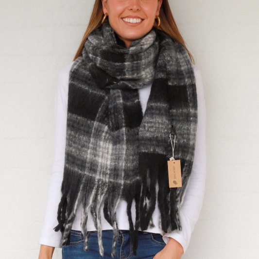 Woman wearing a plaid scarf with a visible brand tag against a white background