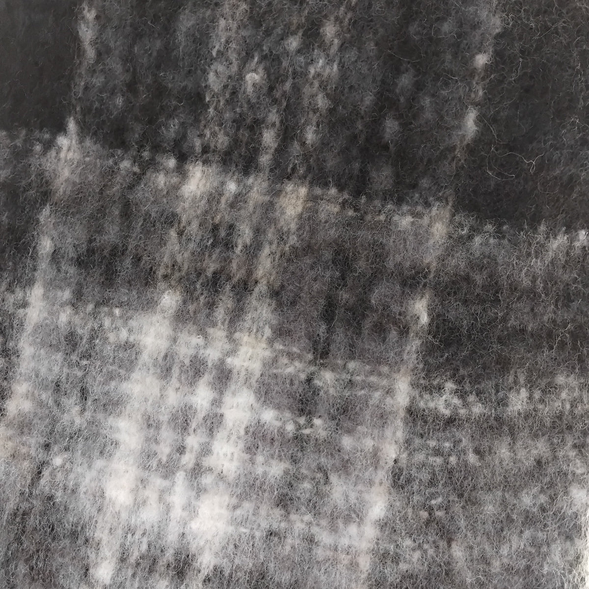 Close-up of a textured ladies chunky scarf in black and white plaid pattern.