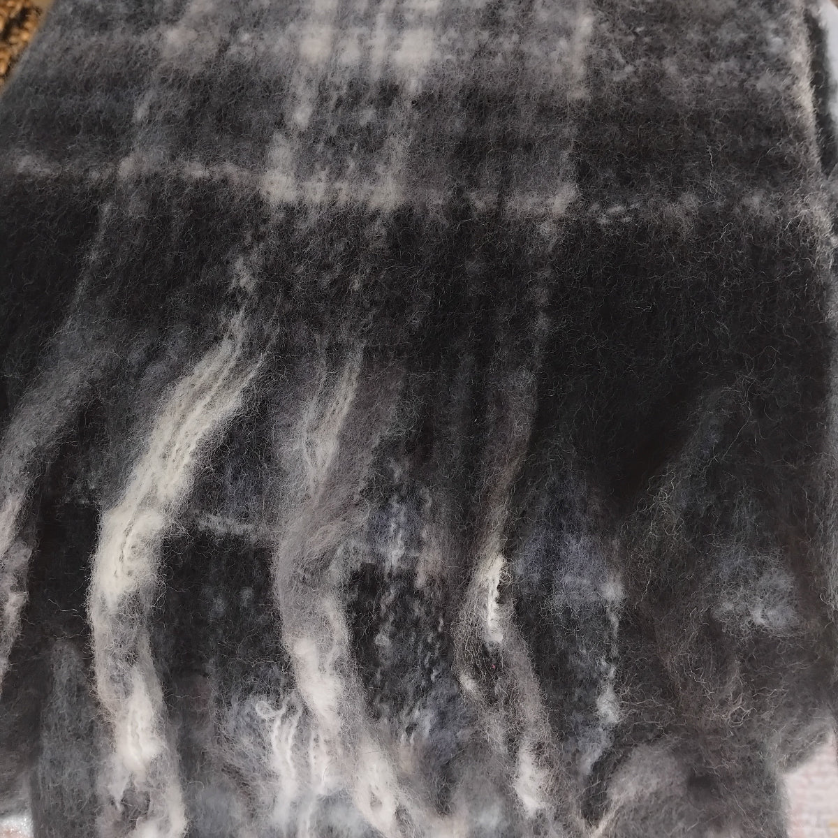 Close-up of a textured black and gray ladies scarf with a chunky fringe