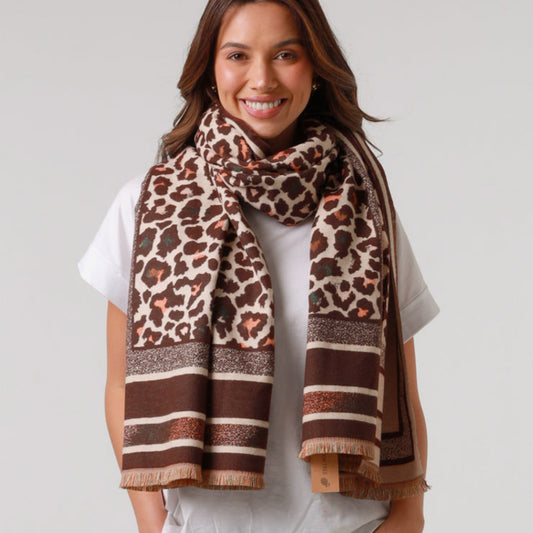 Woman wearing a leopard print scarf with brown and beige patterns on a plain background