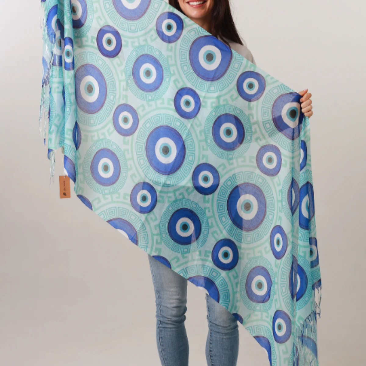 Woman holding a large blue and green patterned scarf against a white background