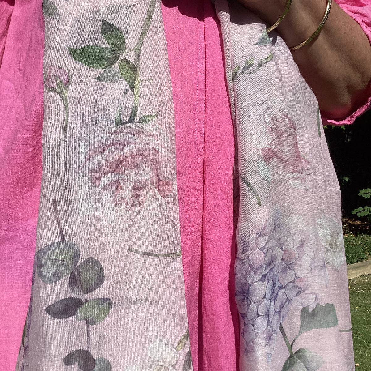 Person holding a floral fabric with pink roses and green foilage