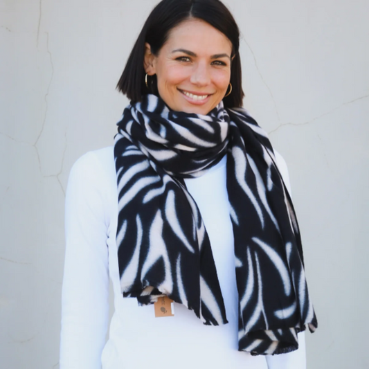 Woman wearing a black and white patterned scarf against a plain background