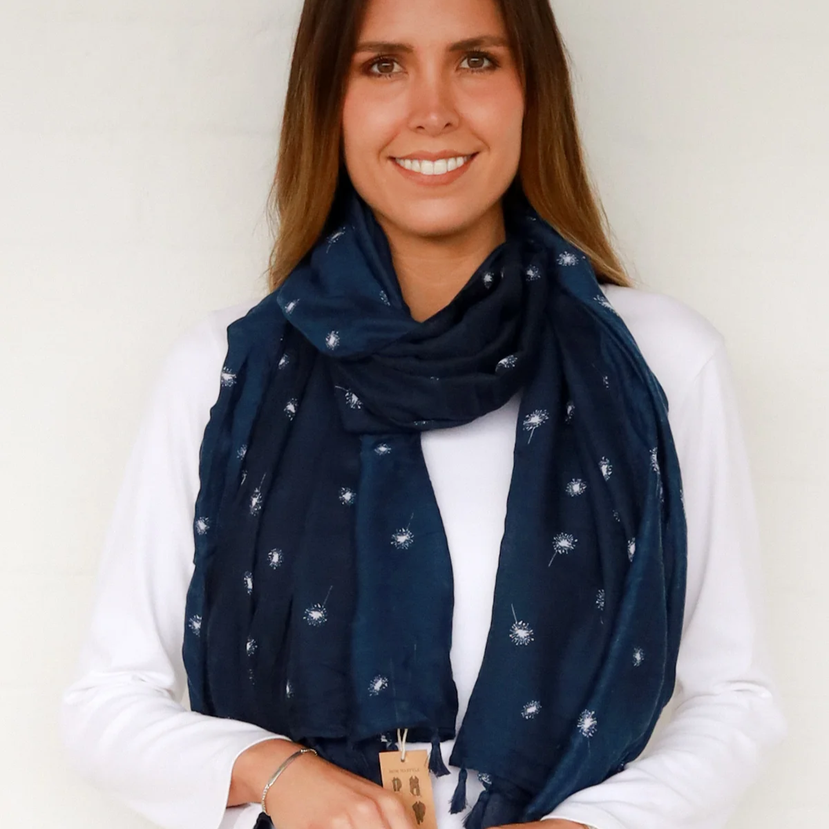 Woman wearing a navy blue scarf with white dandelion pattern against a white background