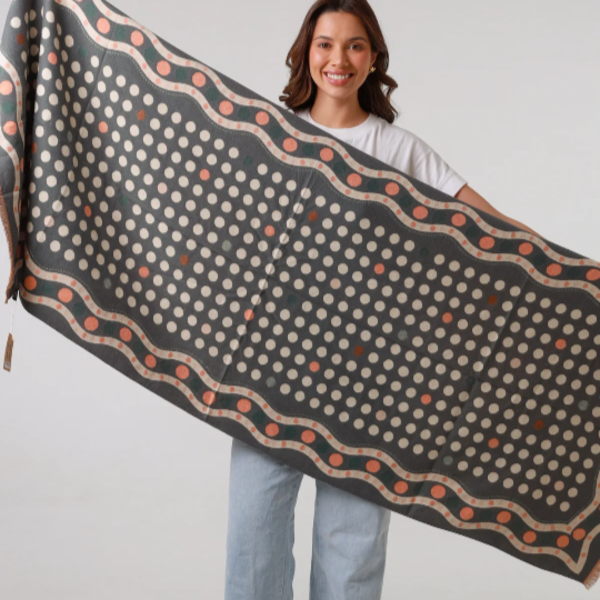 Woman holding a large patterned scarf against a white background