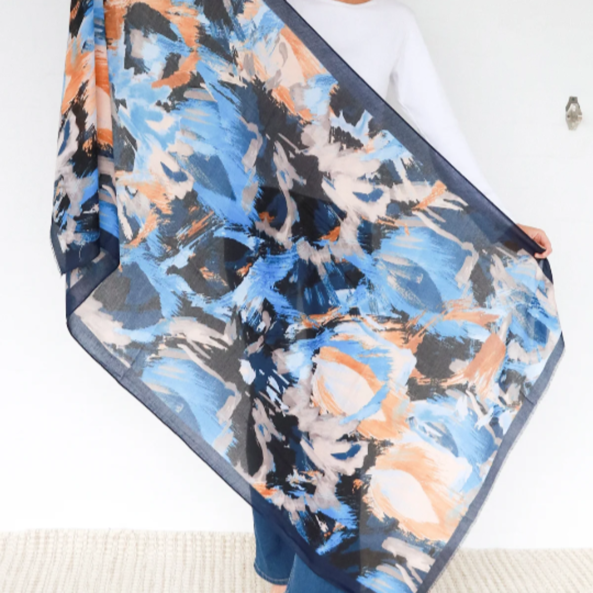 Woman holding an abstract patterned scarf against a white background