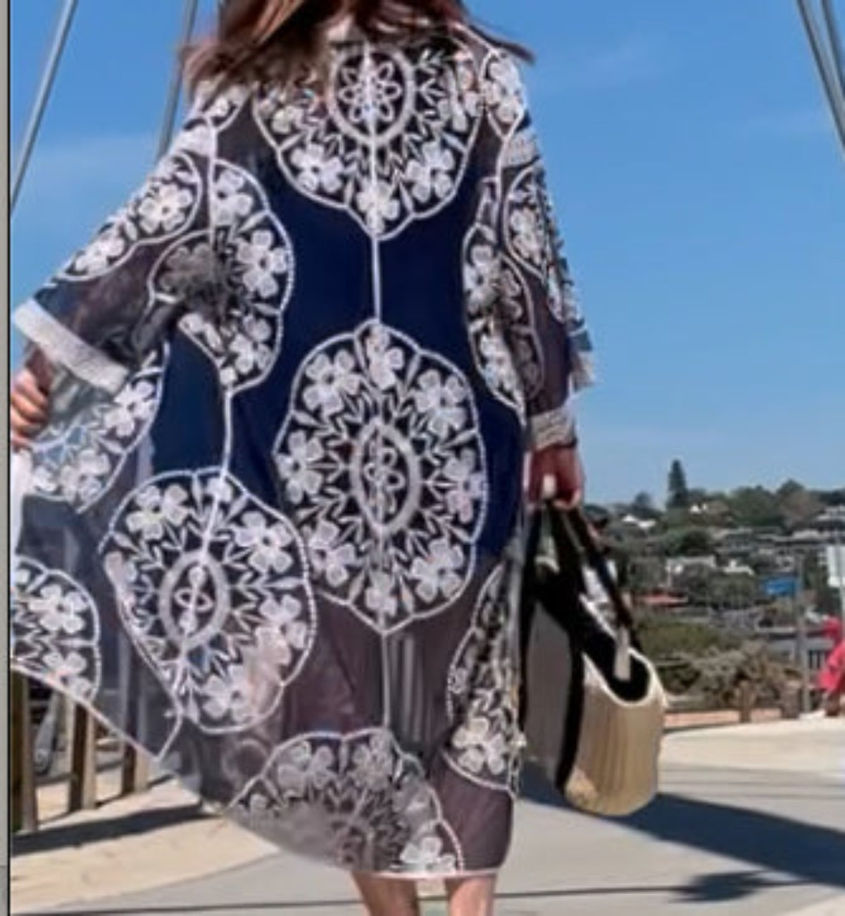 Person wearing a navy kimono with white lace patterns on a sunny day.