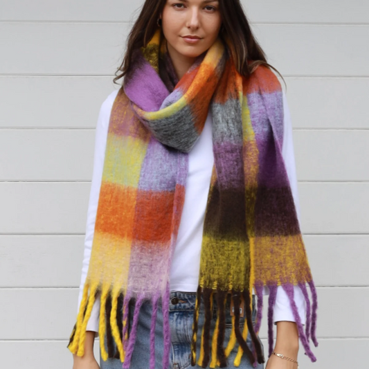 Woman wearing a colorful plaid scarf against a light background
