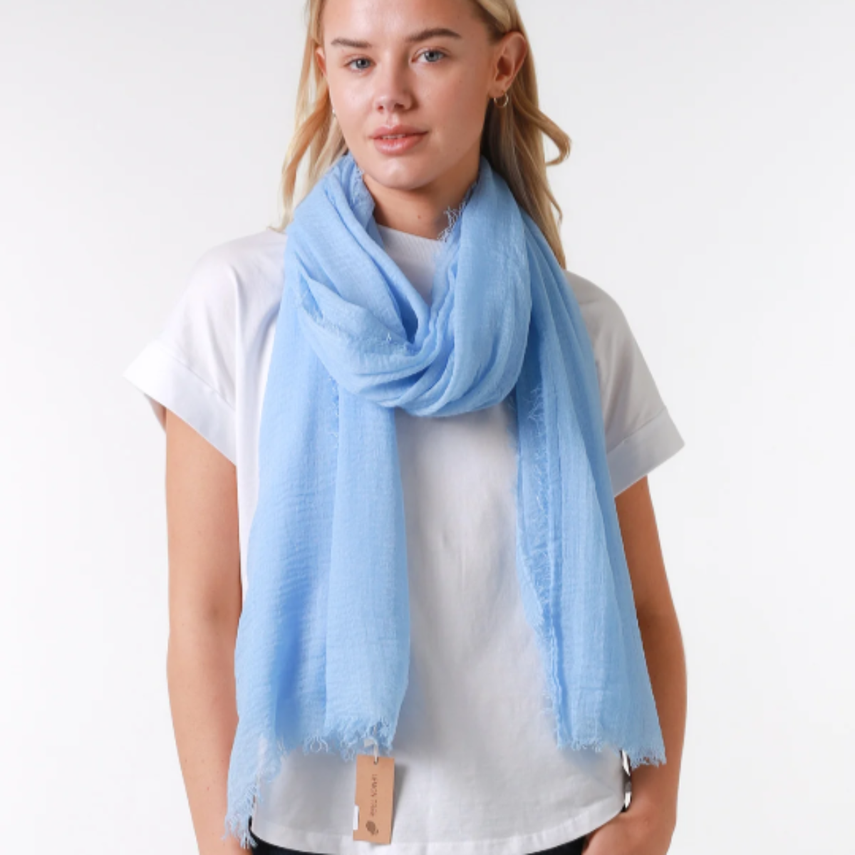 a lady wearing a plain light blue scarf that has a textured weave and a frayed edge on all sides.