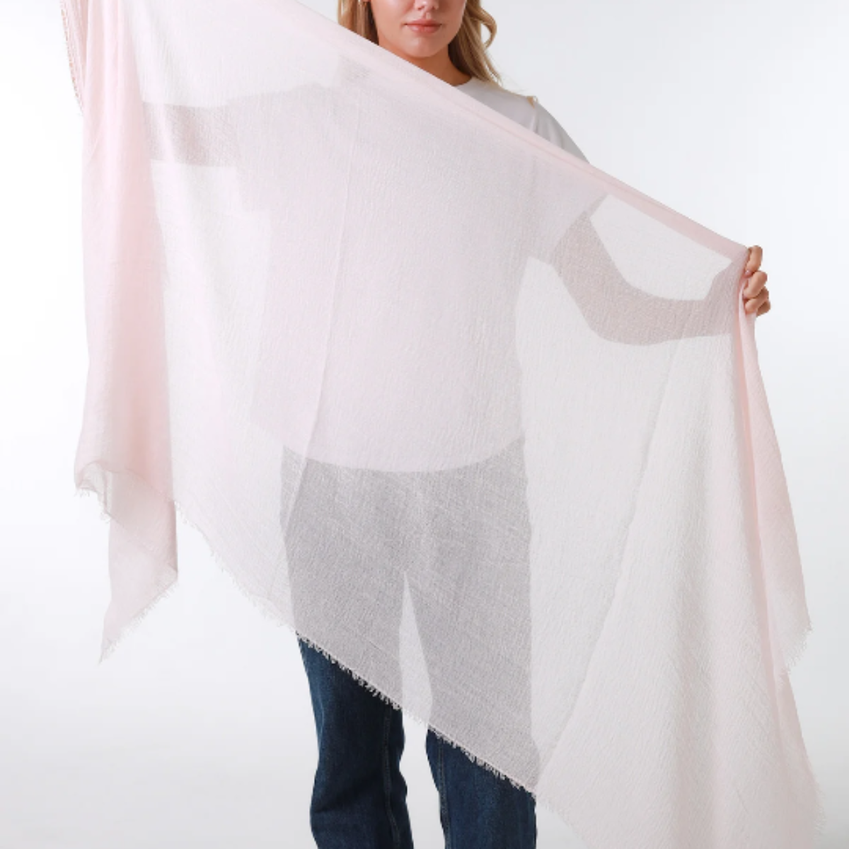 Woman wearing a light pink scarf over a white shirt on a white background