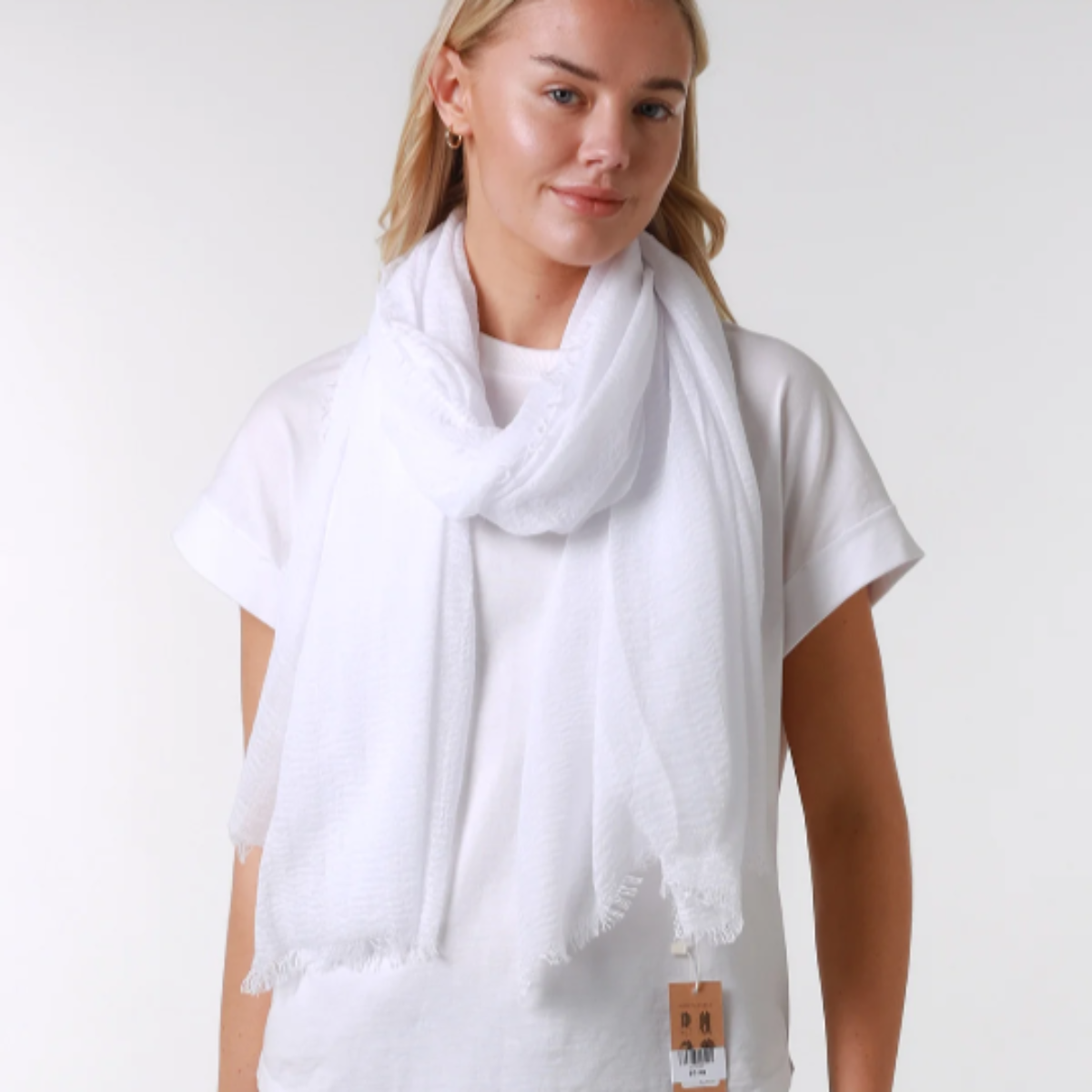 a lady wearing a ladies scarf that has a loose weave and a frayed edge on all sides.