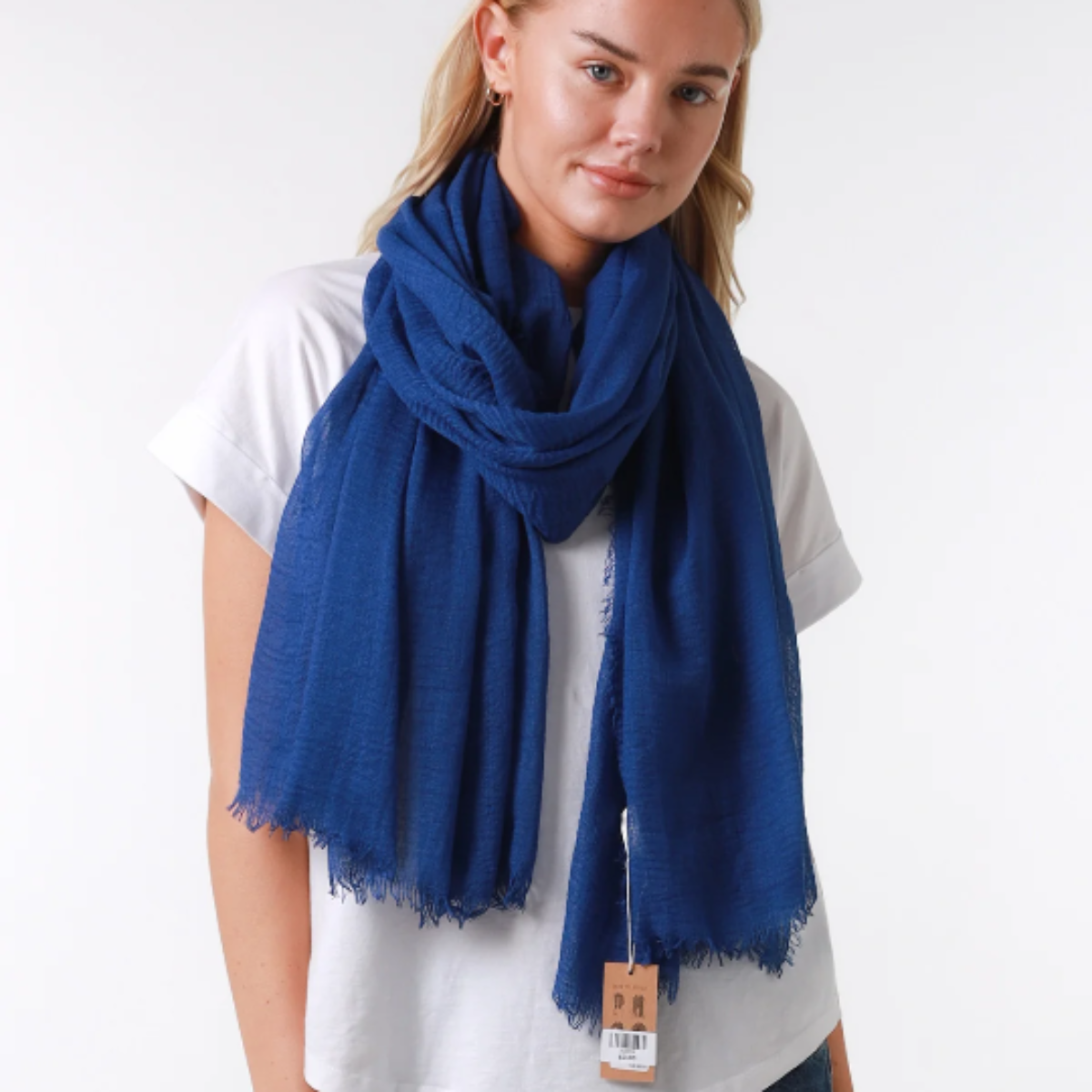 a lady wearing a plain royal blue coloured scarf. The scarf has a loose, textured weave and has a frayed edge on all sides.