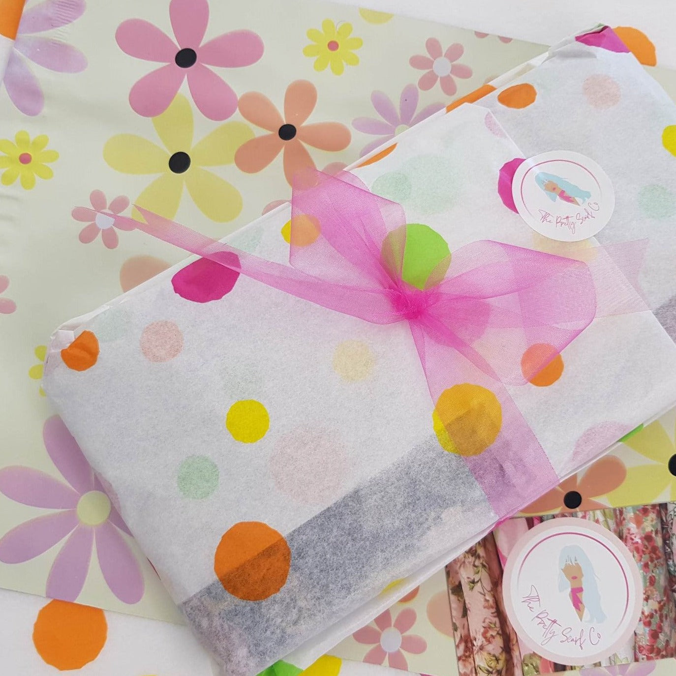 a ladies scarf that has been wrapped in confetti tissue paper and tied with a pink ribbon.