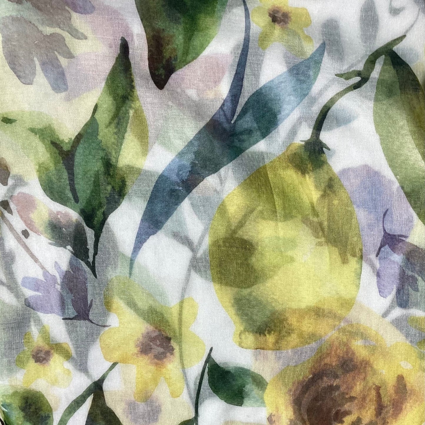 A close up picture of a pretty scarf that has lemons, yellow flowers and green leaves in pretty muted shades.