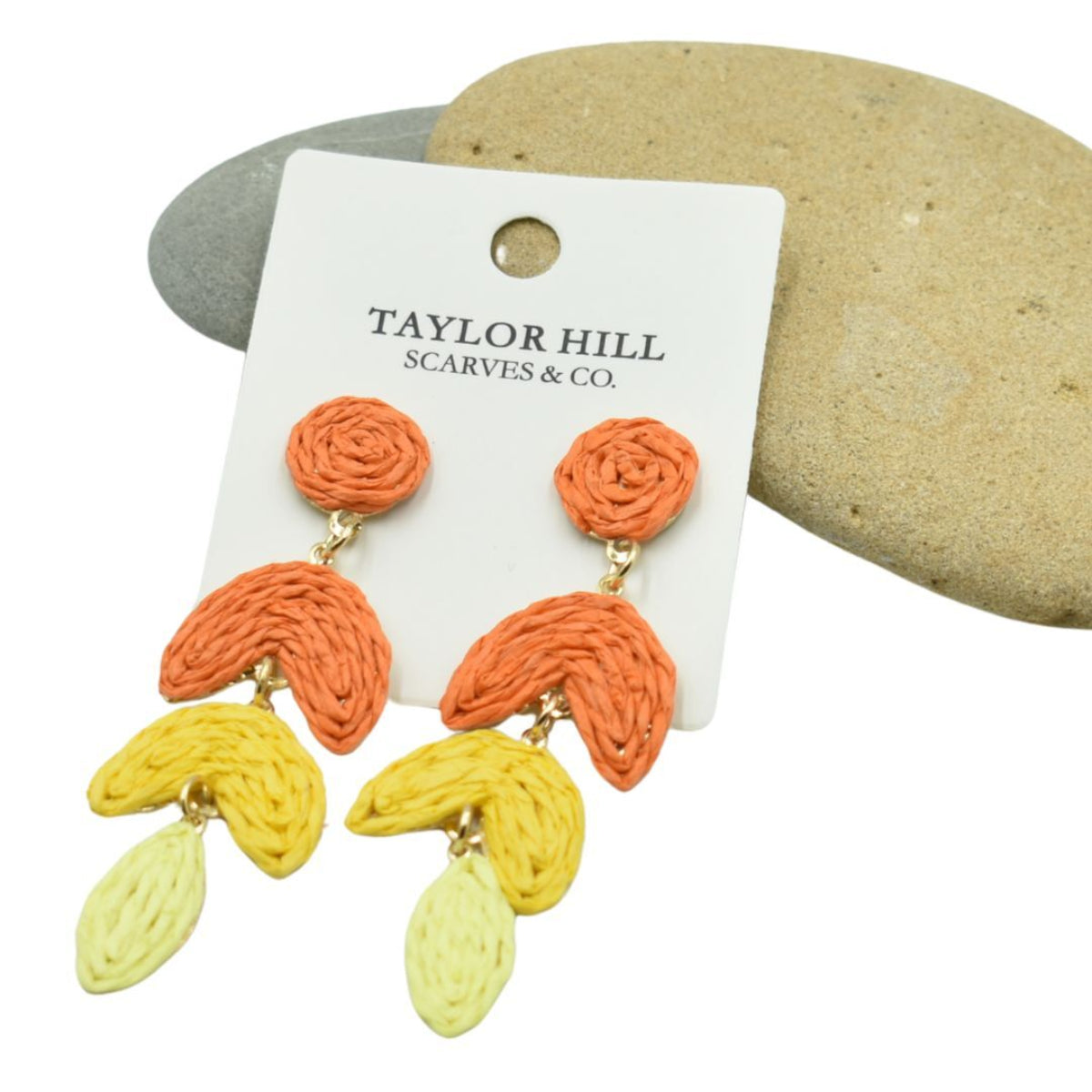 Colorful earrings on a Taylor Hill branded card with stones in the background