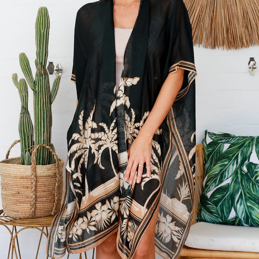 Woman wearing a black floral kimono in a room with a cactus and decorative pillows.