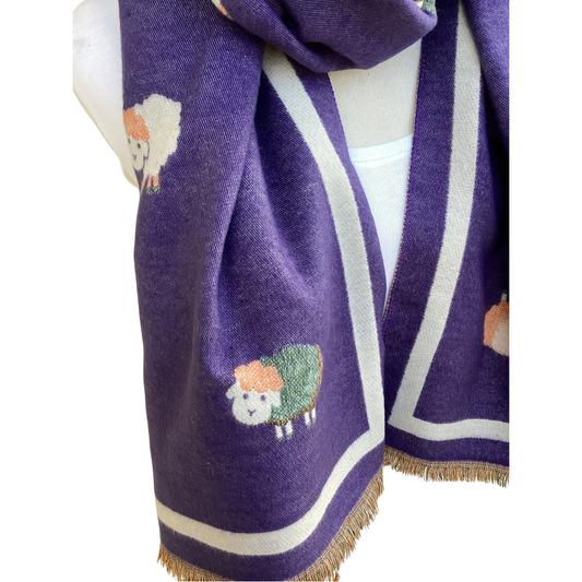 A purple knit scarf with cream borders and embroidered sheep motifs, draped over a white mannequin torso against a white background.
