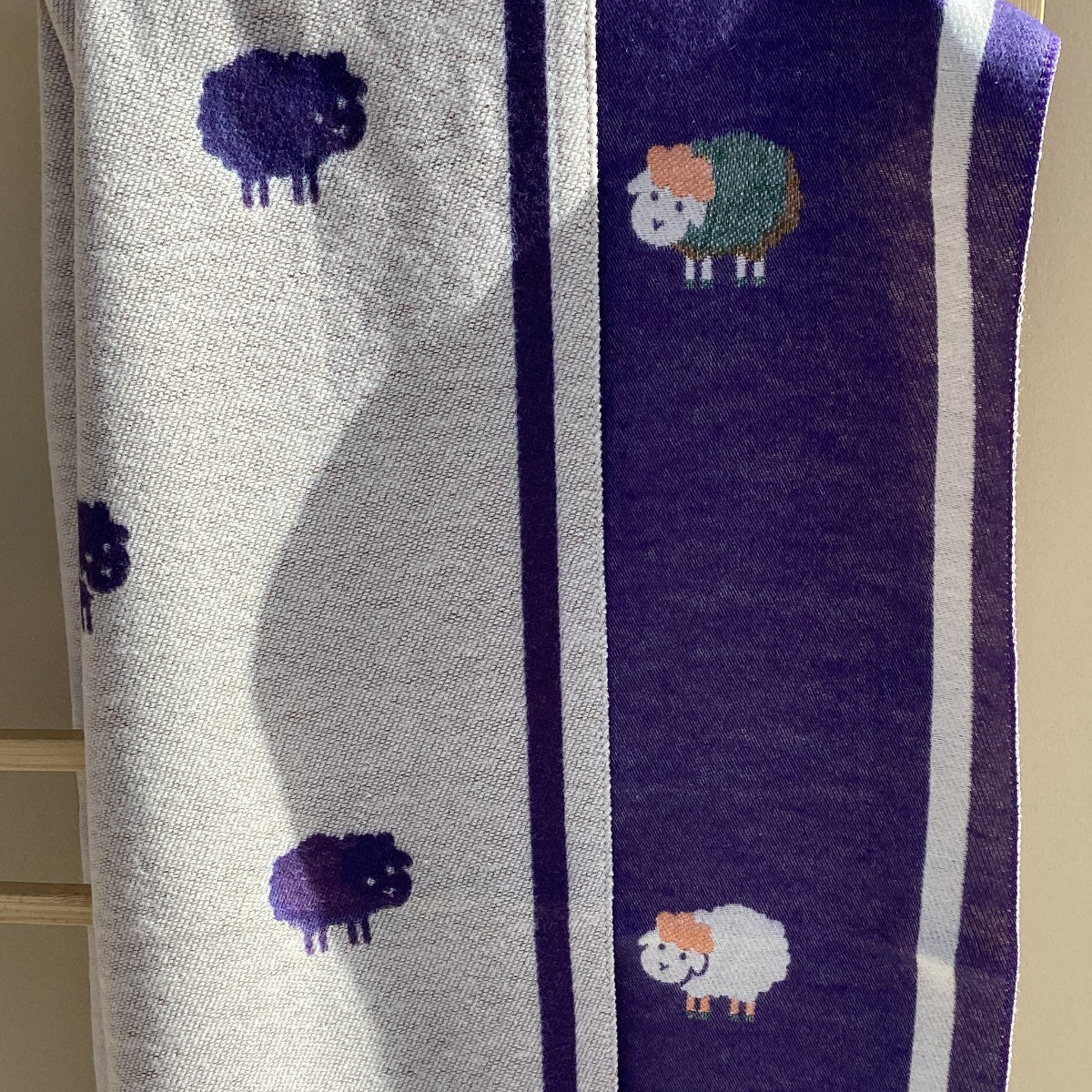 a folded purple scarf with a sheep pattern.