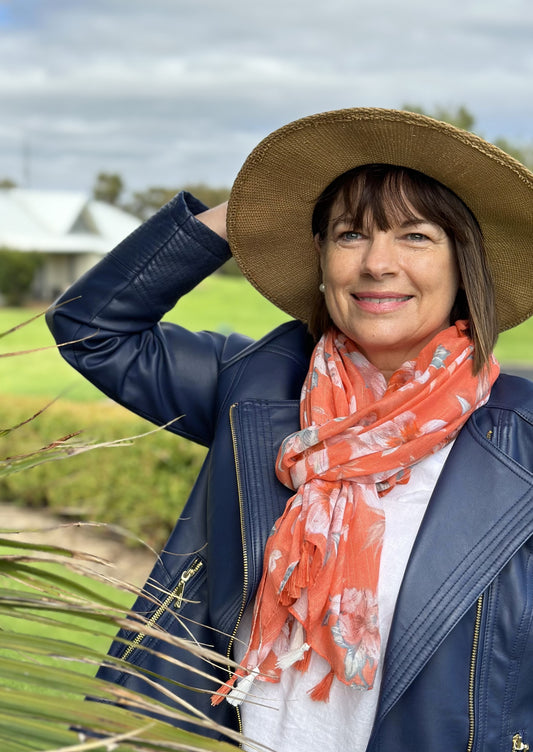 lady wearing tangerine coloured floral scarf with a navy jacket and hat