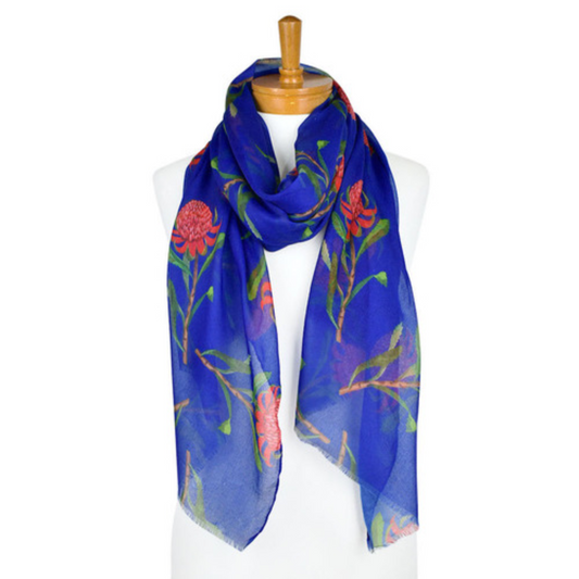 a lightweight cotton scarf that has a navy blue background and bright pink Waratah flowers with green stems and leaves. The scarf is draped around a mannequin.