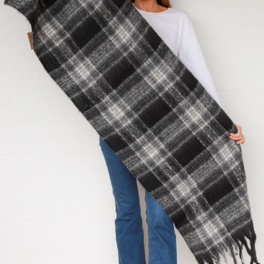 Woman holding a large black and gray plaid scarf against a white background