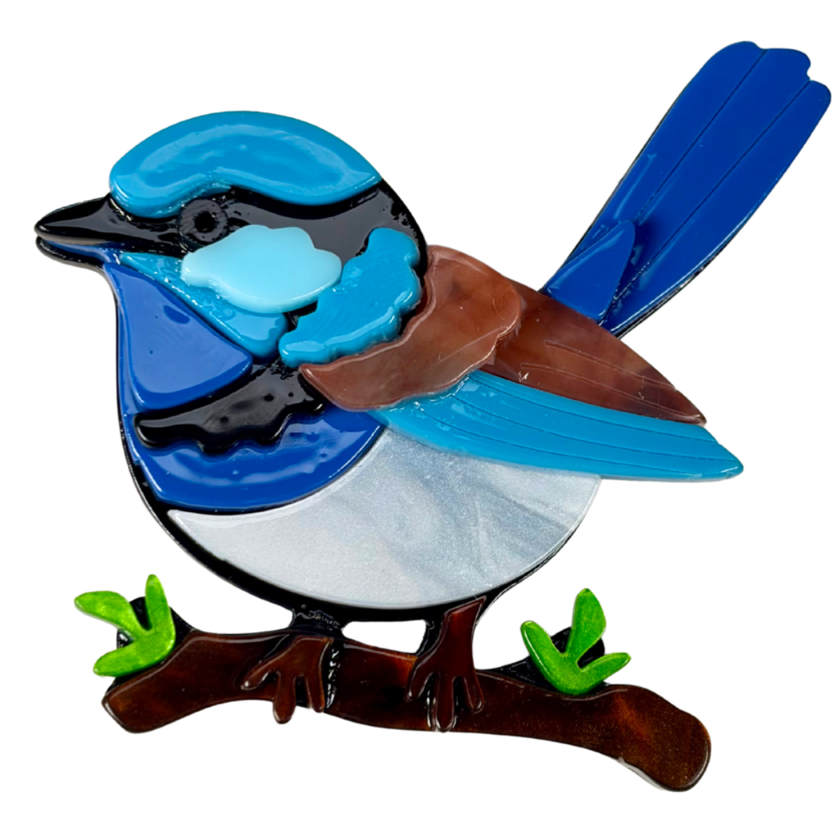 an acrylic brooch of a blue fairy wren sitting on a branch with leaves 