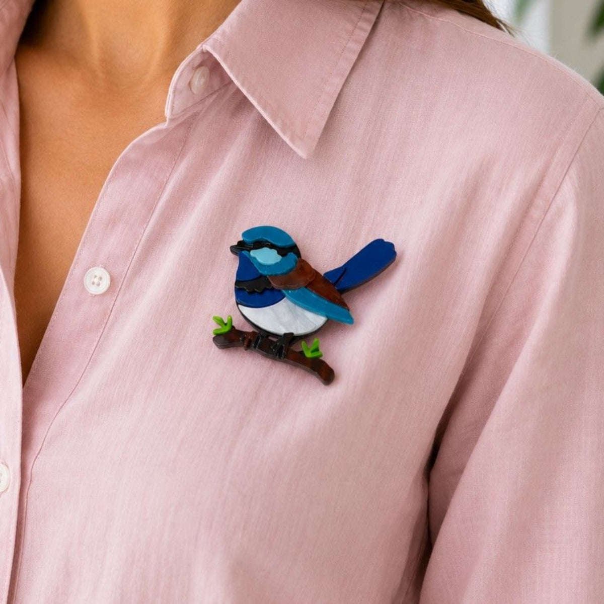 a lady wearing a pink shirt with an acrylic brooch in the shape of a blue wren sitting on a branch