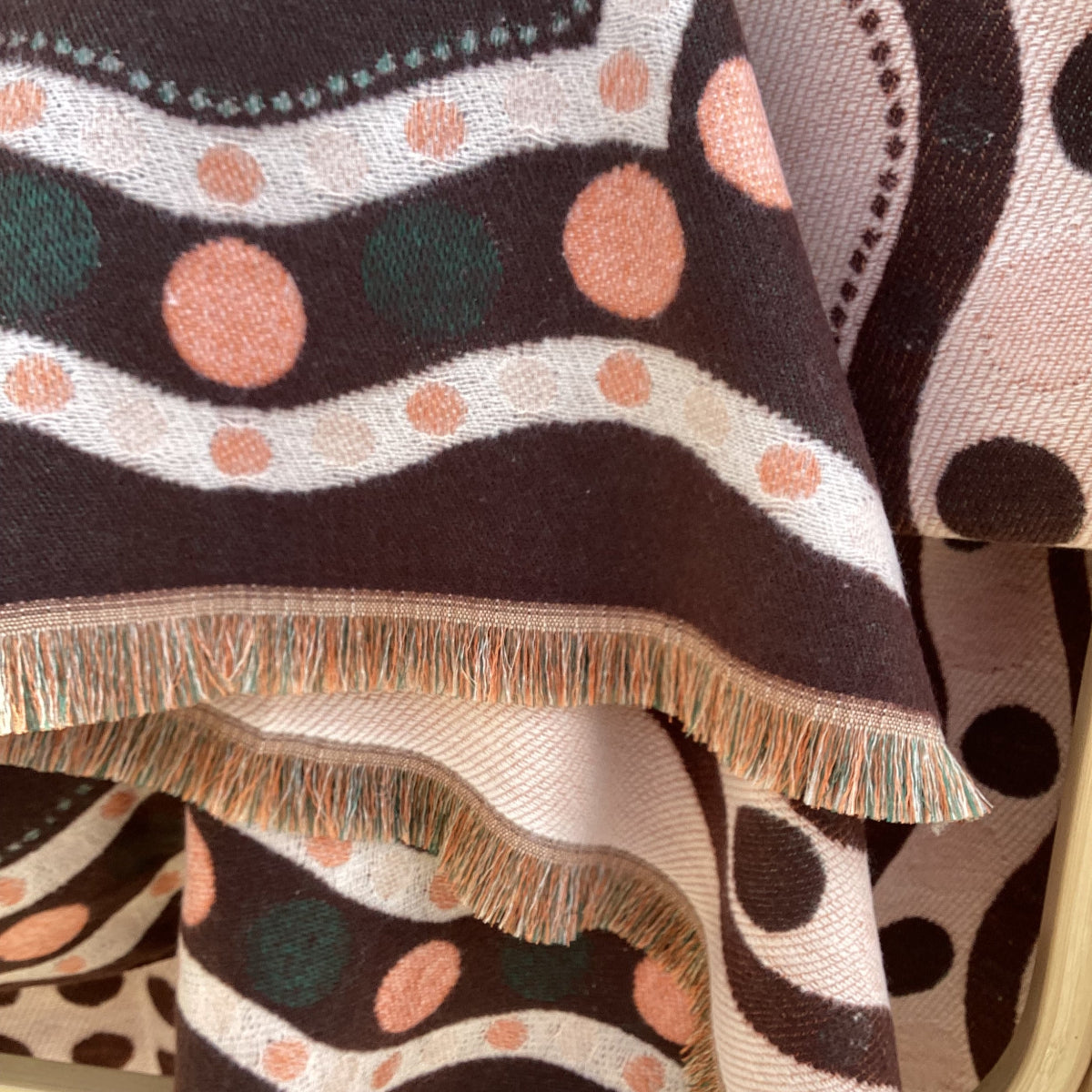 Close-up of a patterned scarf with polka dots and wavy lines.