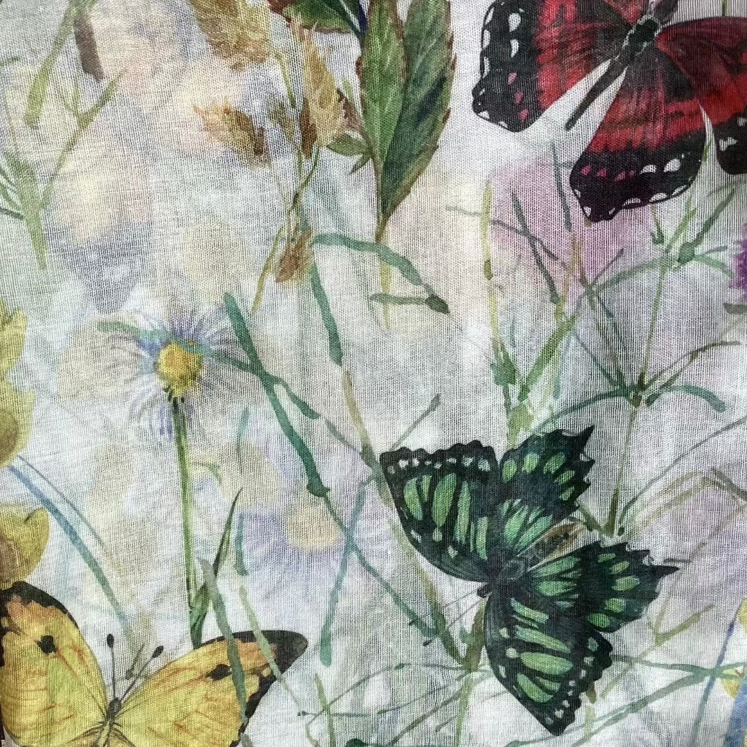 a close up view of the butterfly garden ladies scarf showing green, red and yellow butterflies amongst pretty wild flowers and leaves