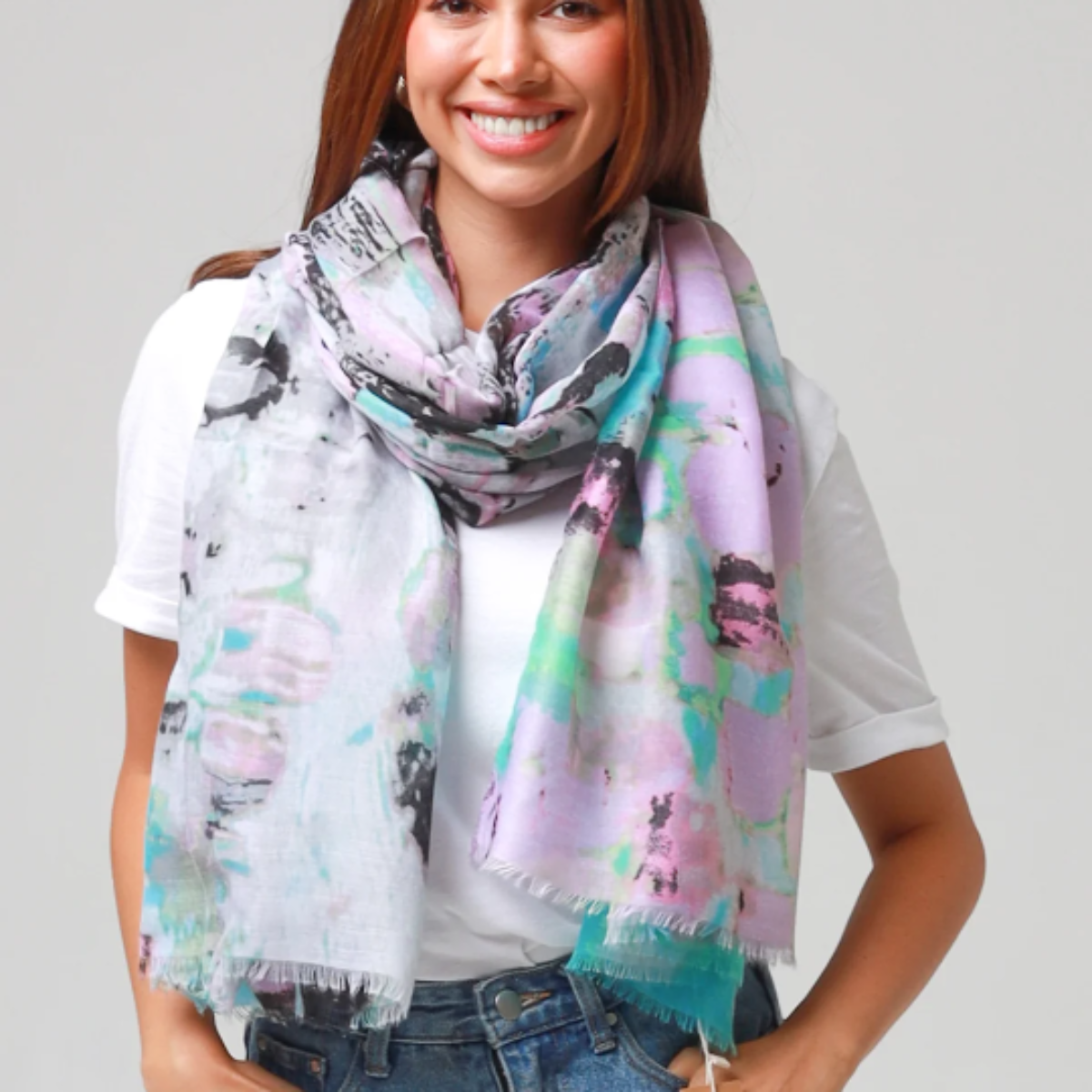 Woman wearing a colorful scarf with abstract patterns on a plain background