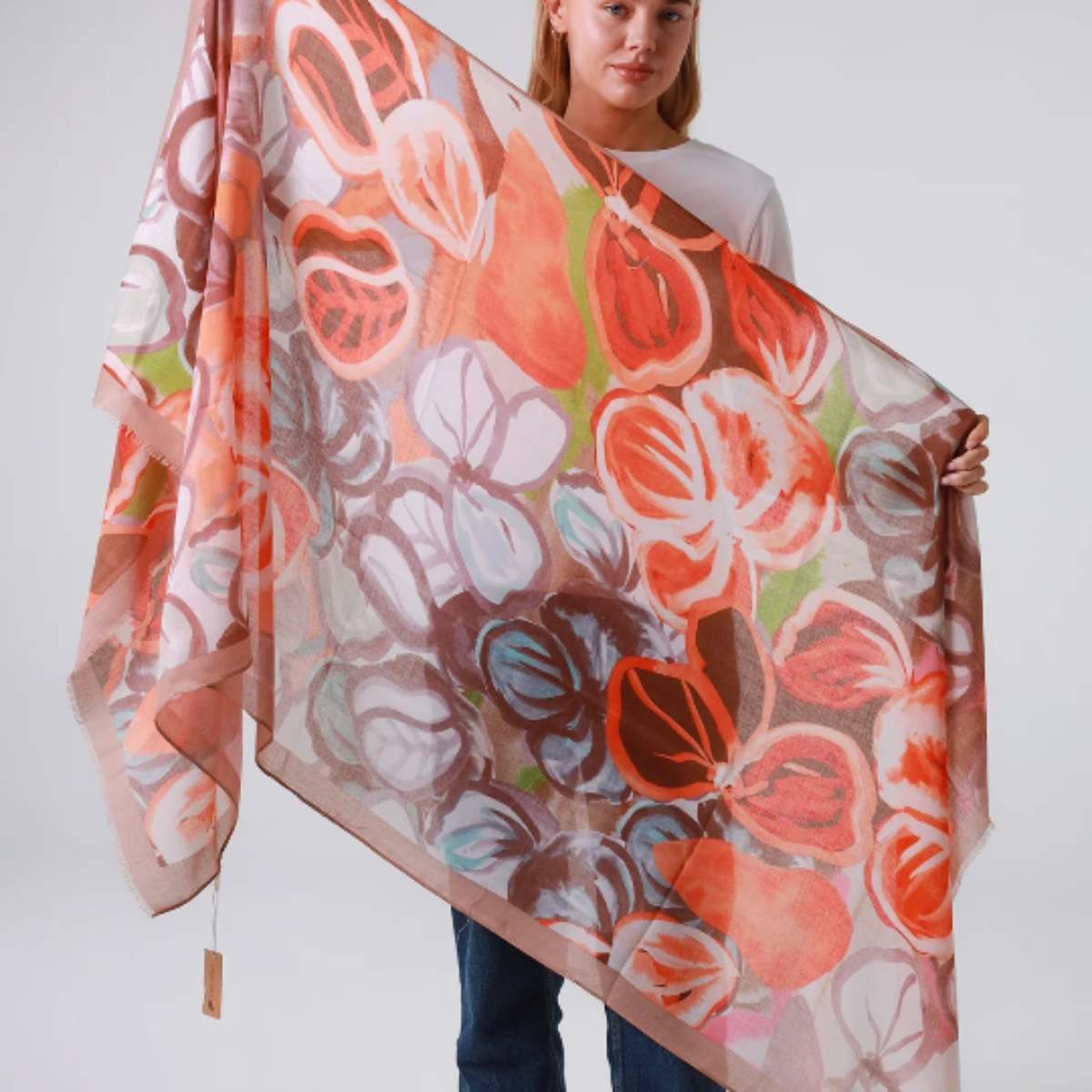 Woman holding a large floral patterned scarf against a white background