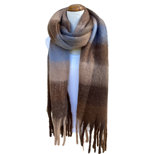 A long, wide scarf with a soft gradient pattern transitioning from beige and brown to light blue, draped on a white mannequin torso with fringed ends.