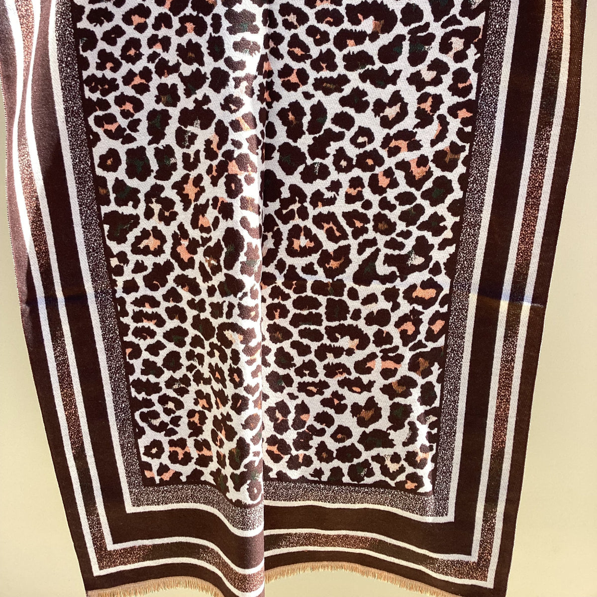 Leopard print scarf with a brown border on a beige background