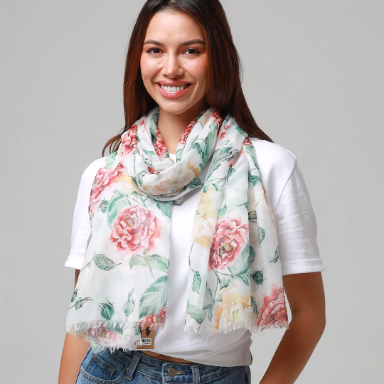 Woman wearing a floral scarf, white shirt, and blue jeans on a gray background