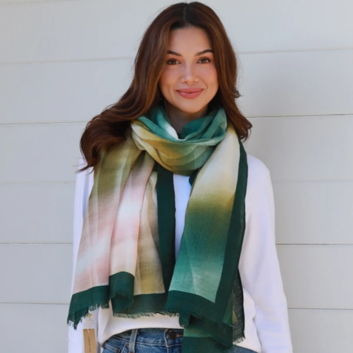 A woman wearing jeans, long seeve white top and a scarf draped around her neck