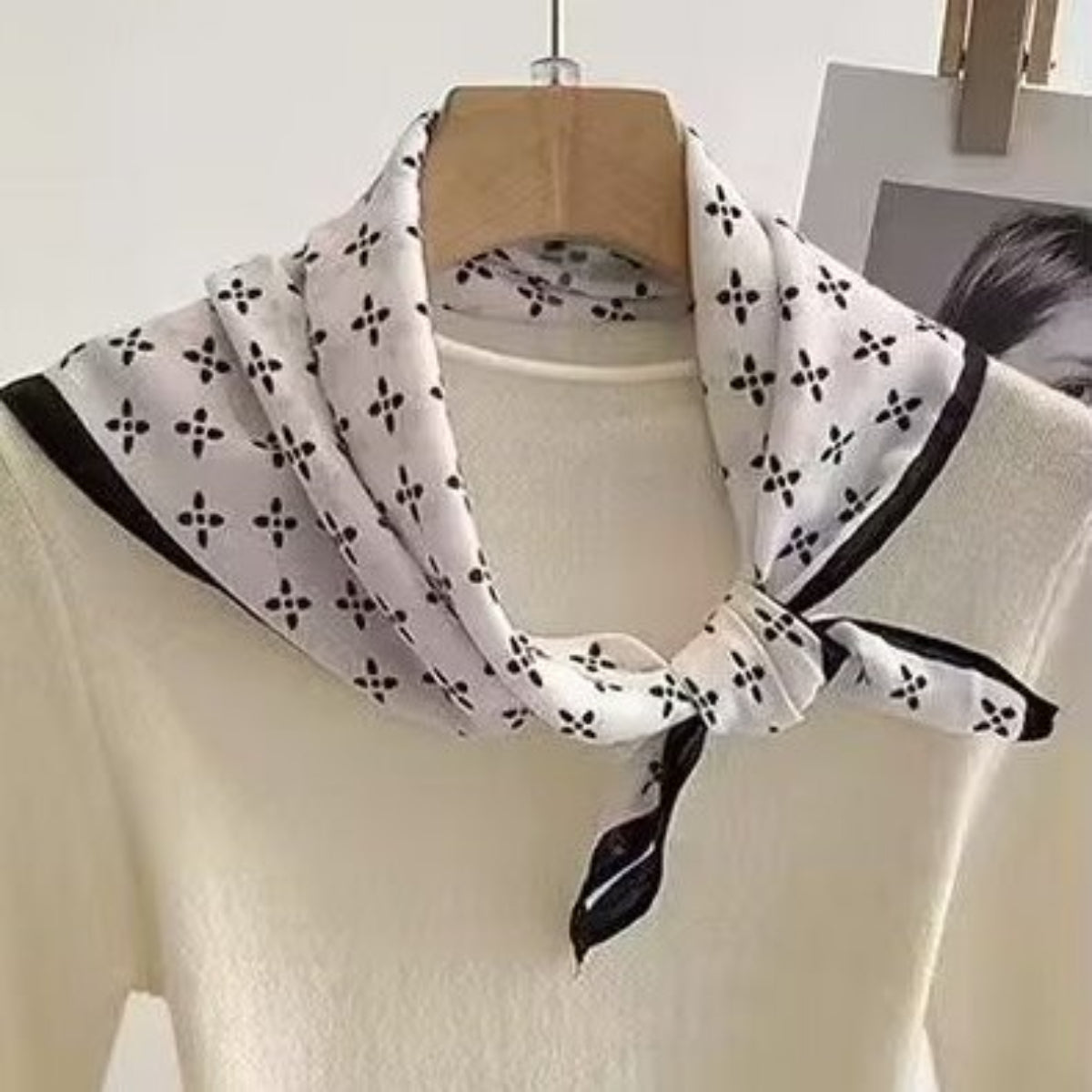 White shirt with a black and white patterned scarf on a hanger against a light background