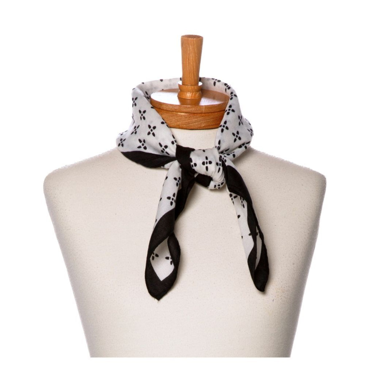 Black and white patterned scarf on a mannequin with a wooden hanger against a white background