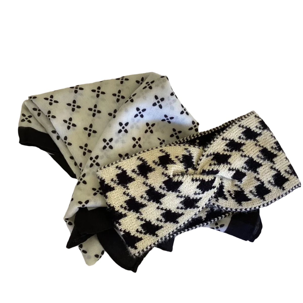 a black and white patterned scarf with a cream and black knitted headband lying on top of the scarf