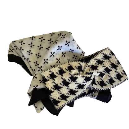 a black and white patterned scarf with a cream and black knitted headband lying on top of the scarf