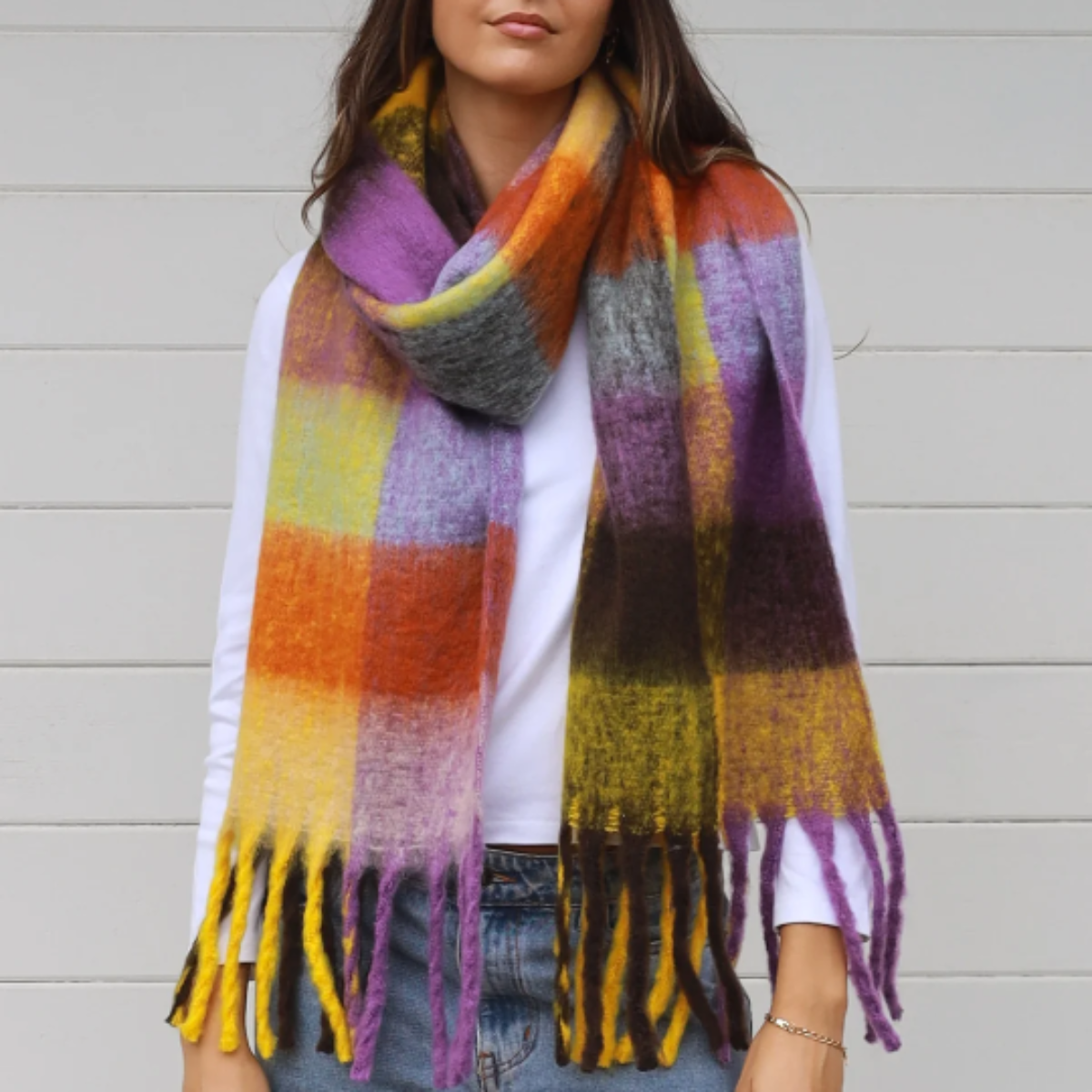 Woman wearing a colorful plaid scarf against a light background