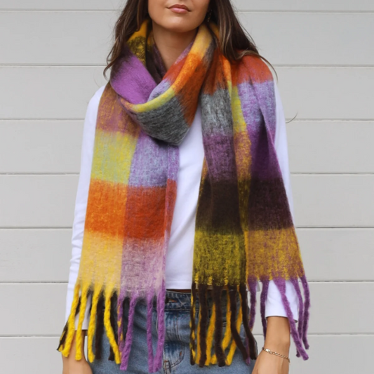 Woman wearing a colorful plaid scarf against a light background