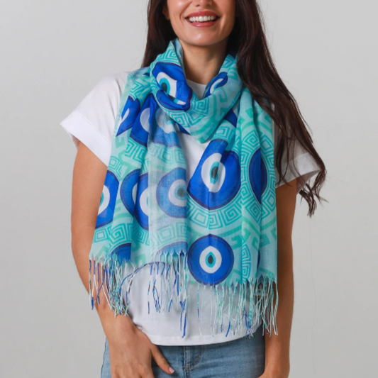 Woman wearing a blue and green Evil Eye patterned scarf on a plain background