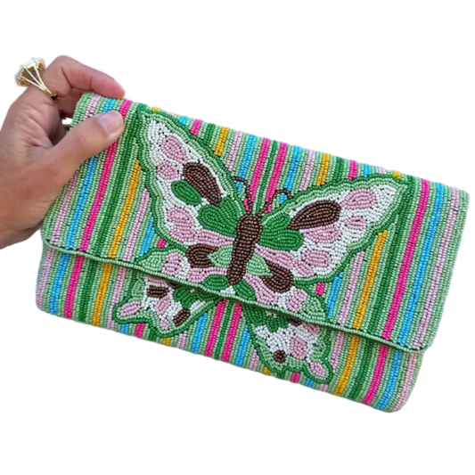 a hand holding a beaded cutch bag that has a green butterfly deign and pink, blue and green stripes