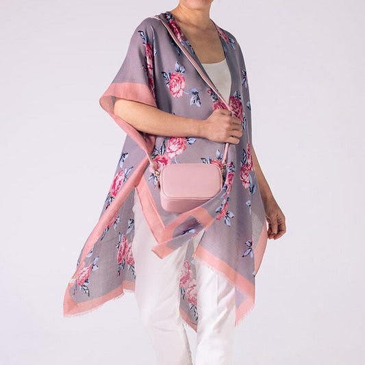 Person wearing a floral kimono-style garment with a pink bag on a white background