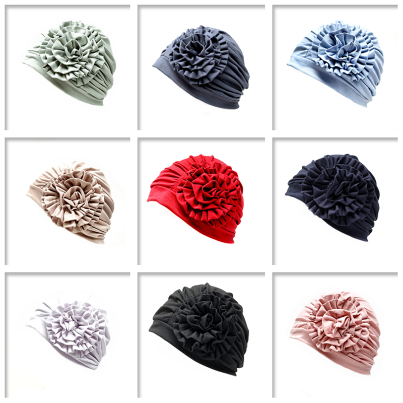 Grid of various plain coloured head turbans that have a flower on the side in different colors on a white background