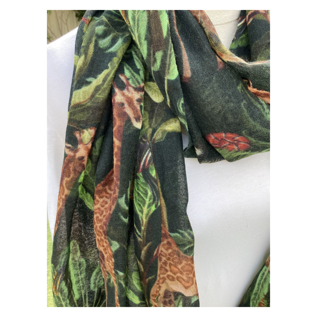 Scarf with giraffe and plant pattern draped over a white surface