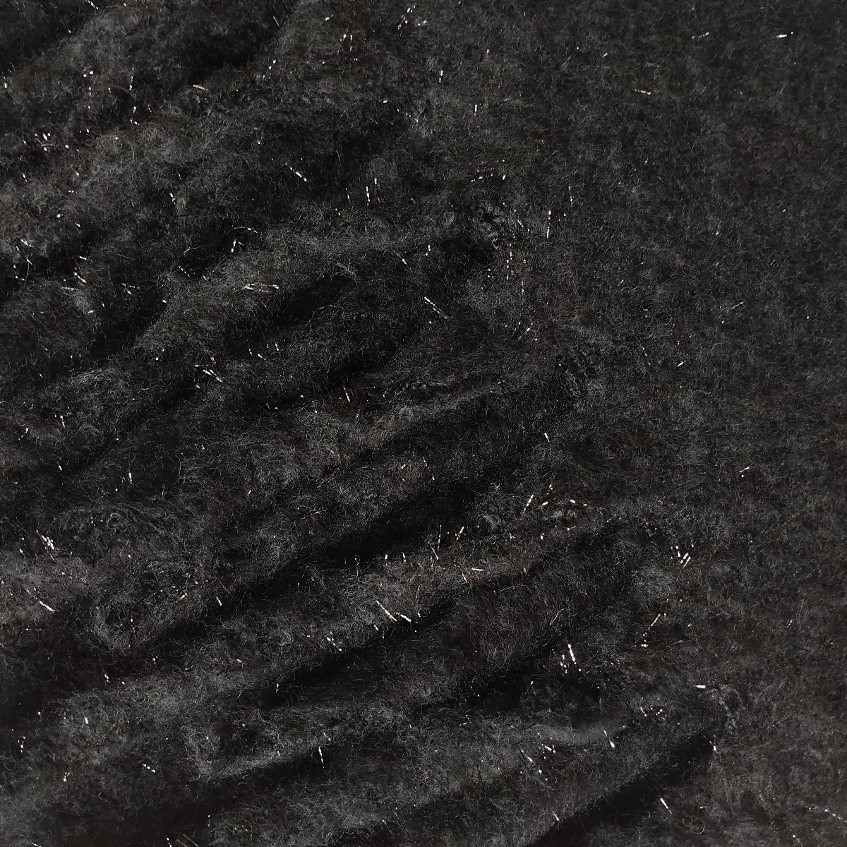 Close-up of textured black knit scarf that has a glitter thread and chunky tassels