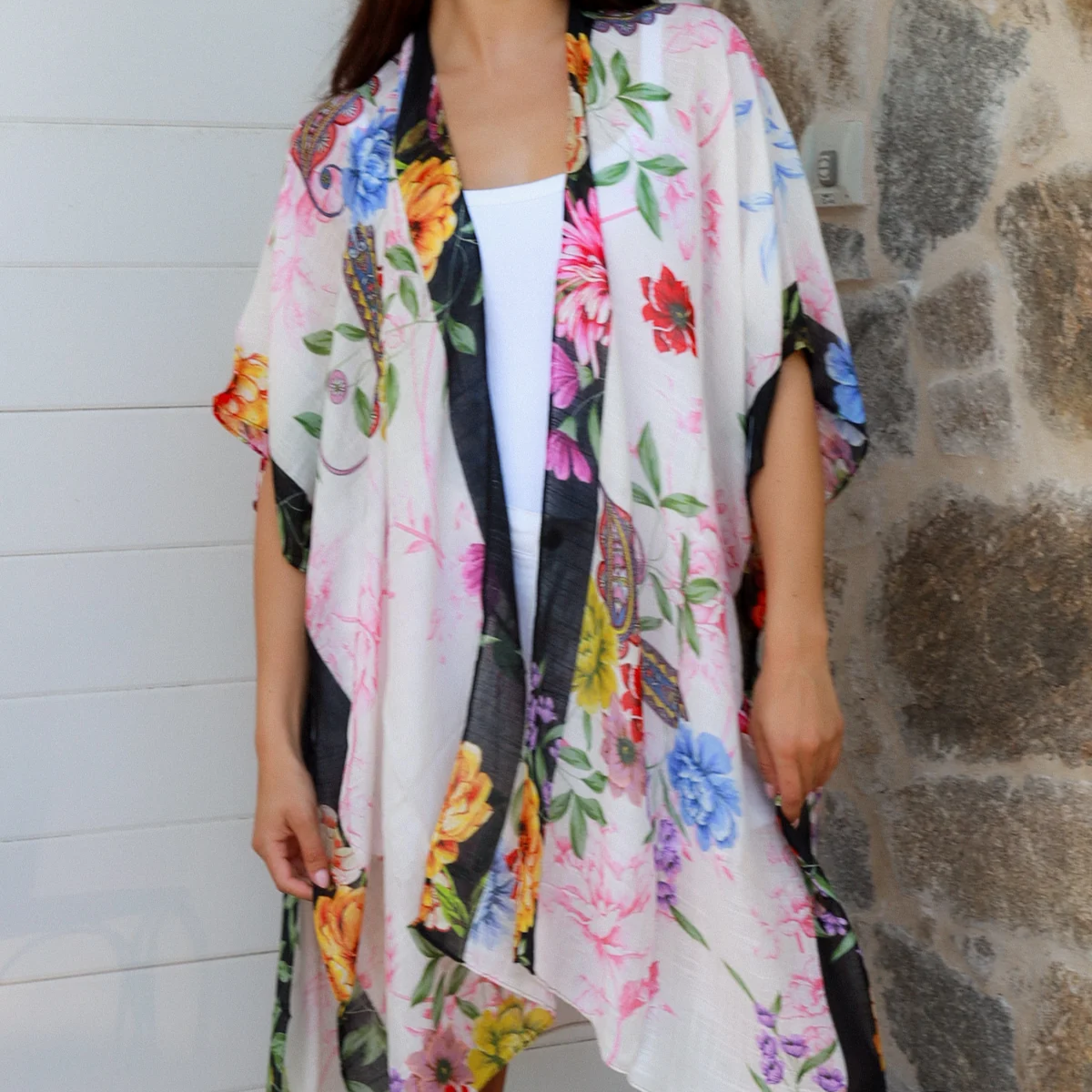 Woman wearing a colorful floral kimono against a stone wall.