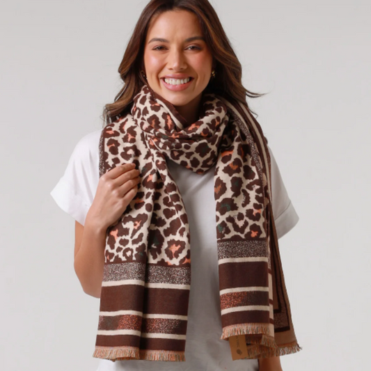 Woman wearing a leopard print scarf with brown and beige patterns on a plain background